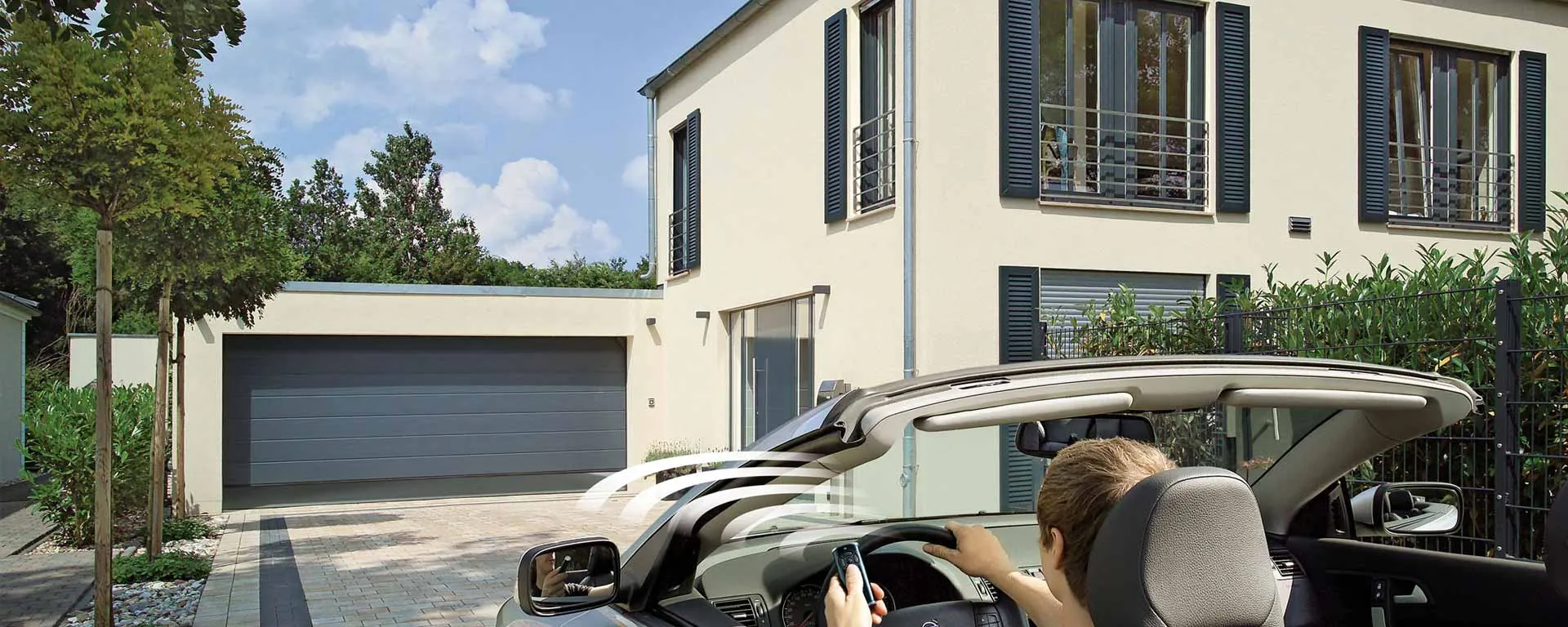 Vozačica otvara garažna vrata daljinskim upravljačem iz automobila